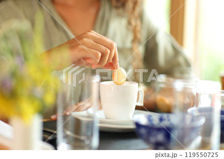 Woman hand dipping cookie in milk in a restaurant Woman hand dipping cookie in milk in a restaurant 119550725