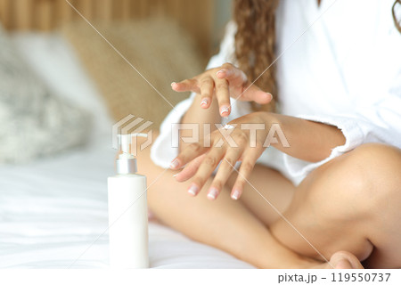 Woman hands applying moisturizer cream on bed Woman hands applying moisturizer cream on bed 119550737