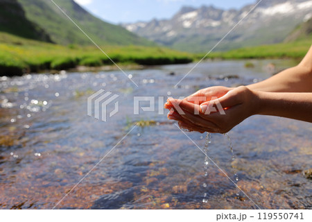 Woman hands catching water from river in the mountain 119550741