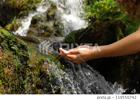 Woman hands cupping catching water from waterfall 119550742