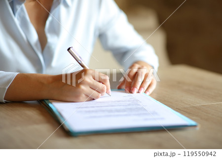 Close up of woman hands signing contract on table 119550942