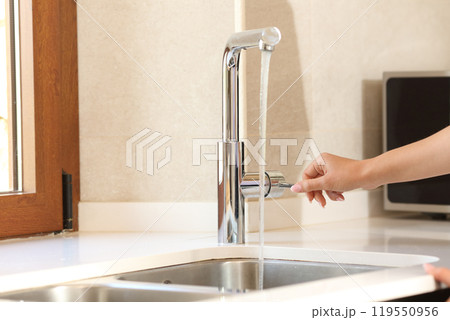 Woman hand opening kitchen faucet 119550956