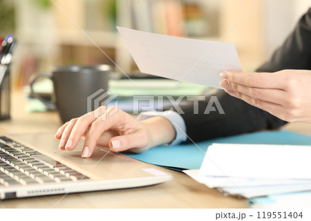 Entrepreneur hands checking receipt with laptop at home 119551404