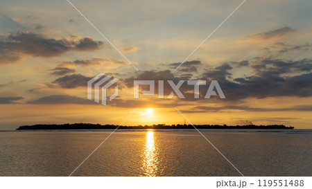 the sun is setting over a small island in the middle of the ocean the sun is setting over a small island in the middle of the ocean 119551488
