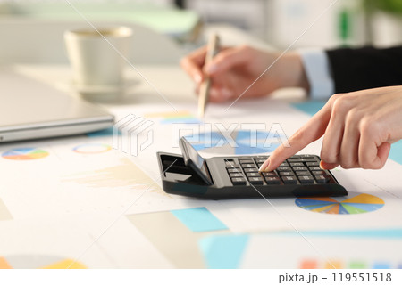 Executive hand calculating with calculator comparing graphs Executive hand calculating with calculator comparing graphs 119551518