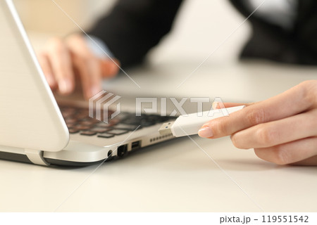 Executive hands plugging pendrive on laptop at office Executive hands plugging pendrive on laptop at office 119551542