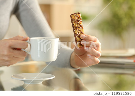 Girl hands holding snack bar and coffee cup at breakfast 119551580