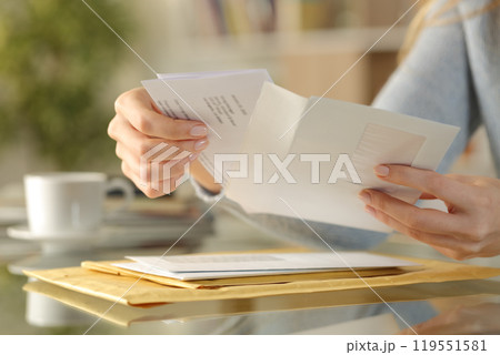 Girl hands opening an envelope on a desk at home Girl hands opening an envelope on a desk at home 119551581