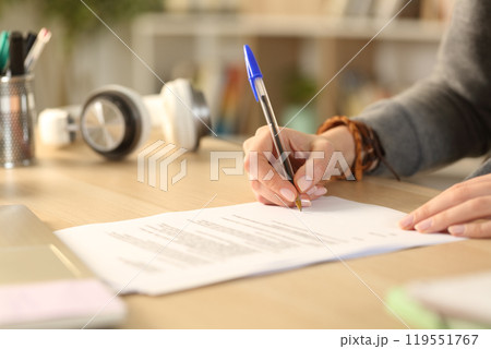 Student hands signing contract at home 119551767