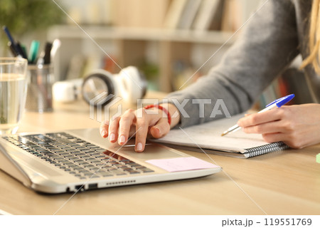 Student hands studying comparing notes with laptop 119551769