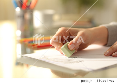 Woman erasing drawing with rubber on desk at home Woman erasing drawing with rubber on desk at home 119551793