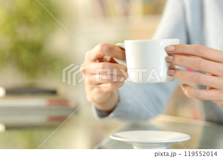 Woman hands holding coffee cup on a desk at home 119552014