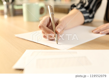 Woman hands writing letter sitting on a desk Woman hands writing letter sitting on a desk 119552079