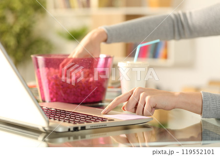 Woman watching streaming tv on laptop with popcorn Woman watching streaming tv on laptop with popcorn 119552101