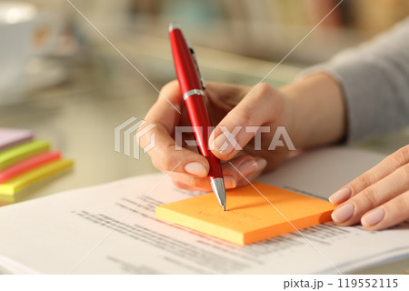 Woman writing to do list on sticky notes on a desk at home 119552115
