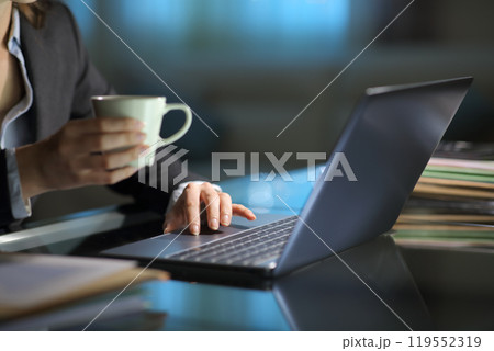 Businesswoman checking laptop content holding coffee 119552319