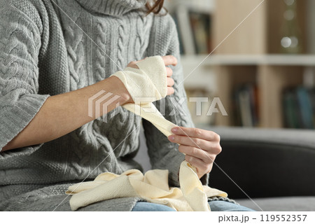 Injured woman hands removing bandage from arm 119552357