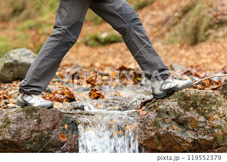 Trekker walking crossing a river in winter 119552379