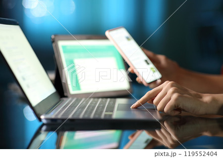 Woman hand using multiple devices in the night at home Woman hand using multiple devices in the night at home 119552404