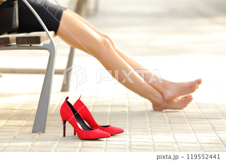 Woman legs taking off high heels resting in a bench 119552441
