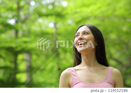 Amazed asian woman walking looking up in a forest 119552586