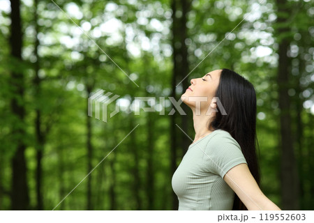 Asian woman breathing fresh air in a forest Asian woman breathing fresh air in a forest 119552603