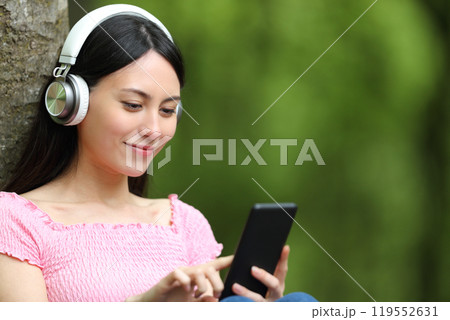 Asian woman listening to music checking smart phone 119552631
