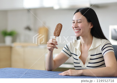 Happy asian woman holding chocolate ice cream in the kitchen Happy asian woman holding chocolate ice cream in the kitchen 119552718