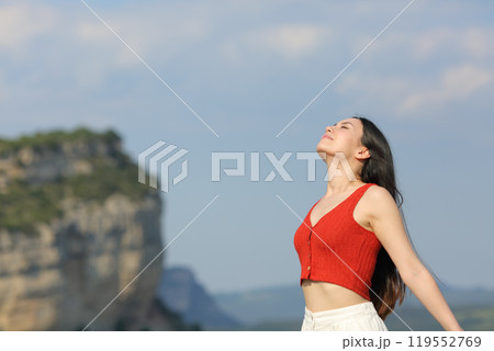 Mixed race woman breathing fresh air in the mountain Mixed race woman breathing fresh air in the mountain 119552769