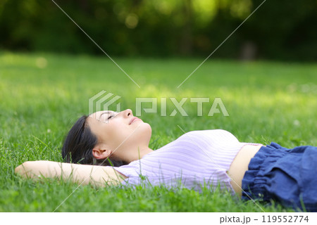 Mixed race woman relaxing lying on the grass 119552774