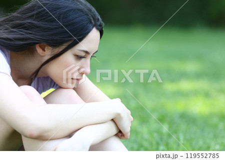 Sad asian woman complaining alone in a park Sad asian woman complaining alone in a park 119552785