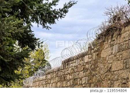 Barbed wire fence on high wall perimeter for security and protection 119554804