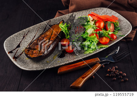 Grilled eggplant served with fresh salad on elegant restaurant table setting 119555719