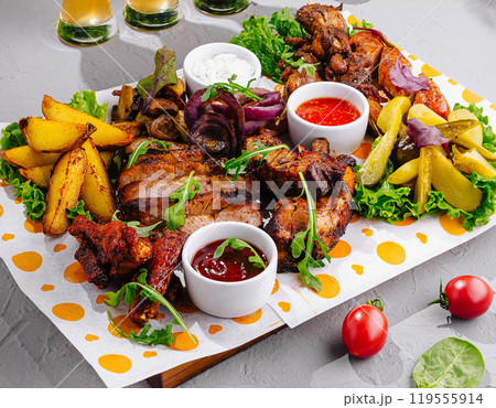 Delicious grilled meat assortment with sauces and potatoes being served on table Delicious grilled meat assortment with sauces and potatoes being served on table 119555914