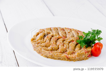 Baba ghanoush decorated with parsley and tomatoes lying on white plate 119555970