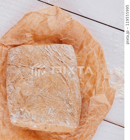 Freshly baked loaf of bread resting on baking paper 119555995