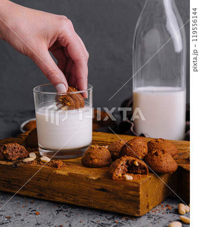 Hand dipping cookie into glass of milk 119556144