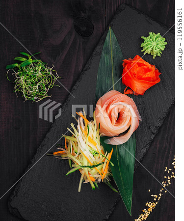 Fresh salmon sashimi beautifully presented on black slate plate 119556161