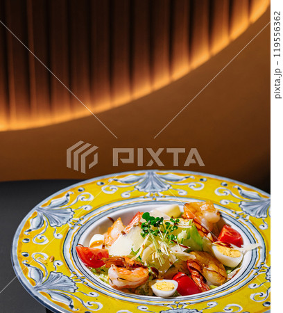 Delicious caesar salad with shrimps sitting on restaurant table Delicious caesar salad with shrimps sitting on restaurant table 119556362