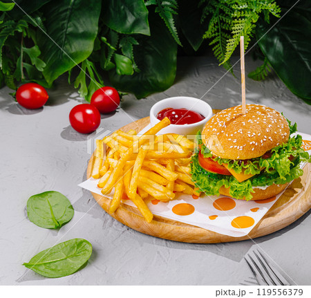 Delicious burger lying on wooden board with french fries and ketchup Delicious burger lying on wooden board with french fries and ketchup 119556379