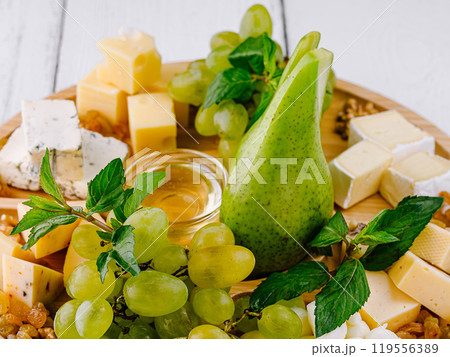 Gourmet cheese plate displayed with grapes and pear on wooden board Gourmet cheese plate displayed with grapes and pear on wooden board 119556389