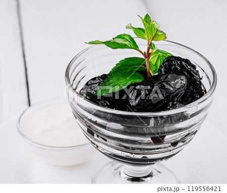 Prunes with mint sprig served in glass on white table 119556421