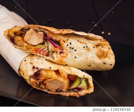 Two delicious chicken shawarma wraps lying on black plate 119556530