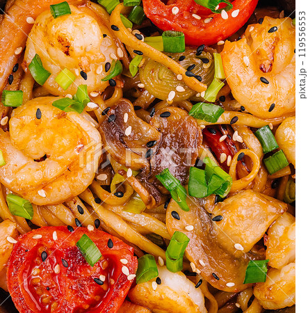 Udon noodles with shrimps and mushrooms garnished with black and white sesame seeds 119556553