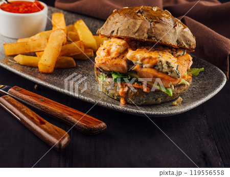 Delicious salmon burger with blue cheese and fries served on gray plate Delicious salmon burger with blue cheese and fries served on gray plate 119556558