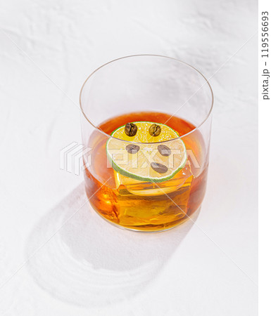 Negroni cocktail standing on white table with harsh shadows Negroni cocktail standing on white table with harsh shadows 119556693