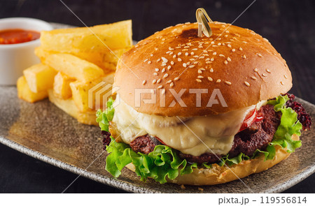 Delicious burger with beef, tomato, cheese and salad served on plate 119556814