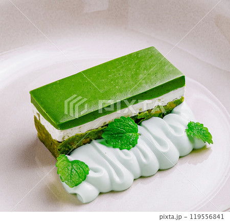 Matcha green tea cake with cream cheese and pistachio paste on white plate 119556841