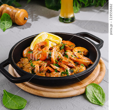 Fried tiger prawns served in cast iron pan with lemon and herbs 119556882