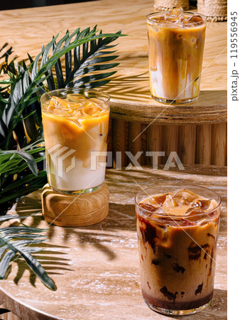 Three iced coffee drinks sitting on a cafe table in the sun Three iced coffee drinks sitting on a cafe table in the sun 119556945